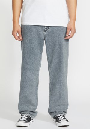 Light grey denim jeans with a straight leg design, featuring a faded texture. Paired with black and white sneakers.