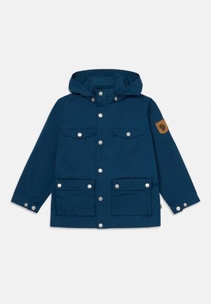 Marineblå hettegenser laget av holdbart stoff, med sølvfargede trykknapper, fire framlommer og en brun logo-manchett på ermene.