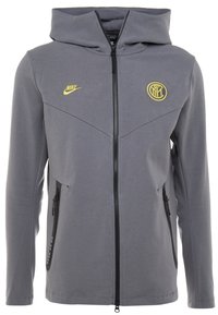 Veste à capuche grise avec fermeture éclair sur le devant, fermetures éclair noires et poches kangourou. Présente un logo Nike jaune et un badge de l'Inter Milan sur la poitrine.