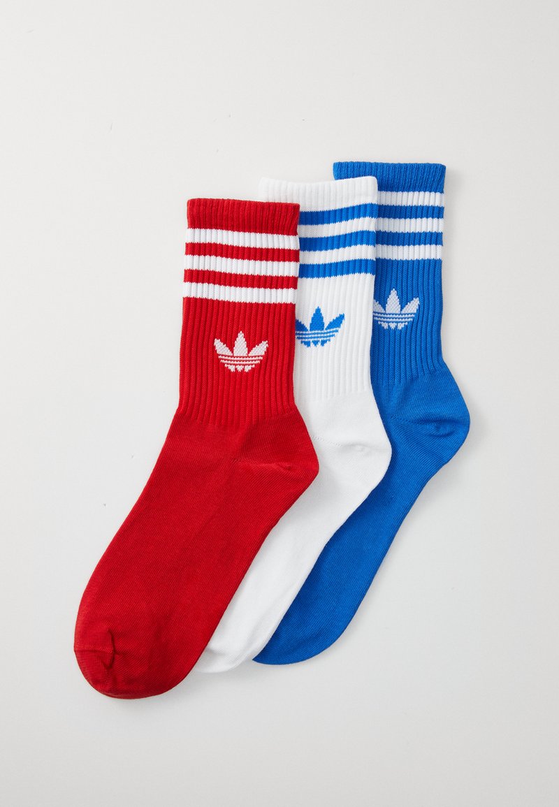 Tre paia di calze sportive: rosse con strisce bianche, bianche con strisce blu e blu. Tessuto rigato con dettagli logo su ogni paio.