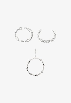 Tre sølvarmbånd: et med aflange led, et andet med store led og et tredje med blomsterdetaljer og en kædeforlænger.