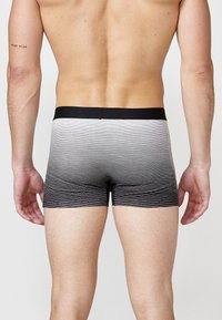 Schwarz-weiße gestreifte Boxershorts mit einem weichen Bund, die ein Farbverlaufsmuster aufweisen, das von hell nach dunkel übergeht.