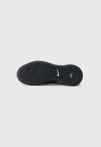 Semelle de sneaker noire avec un motif de grip texturé et logo swoosh blanc de Nike sur un fond blanc uni.