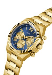 Montre en or avec un boîtier octagonal, un cadran texturé bleu, des chiffres romains, trois sous-cadrans et un bracelet en or avec une finition poli.