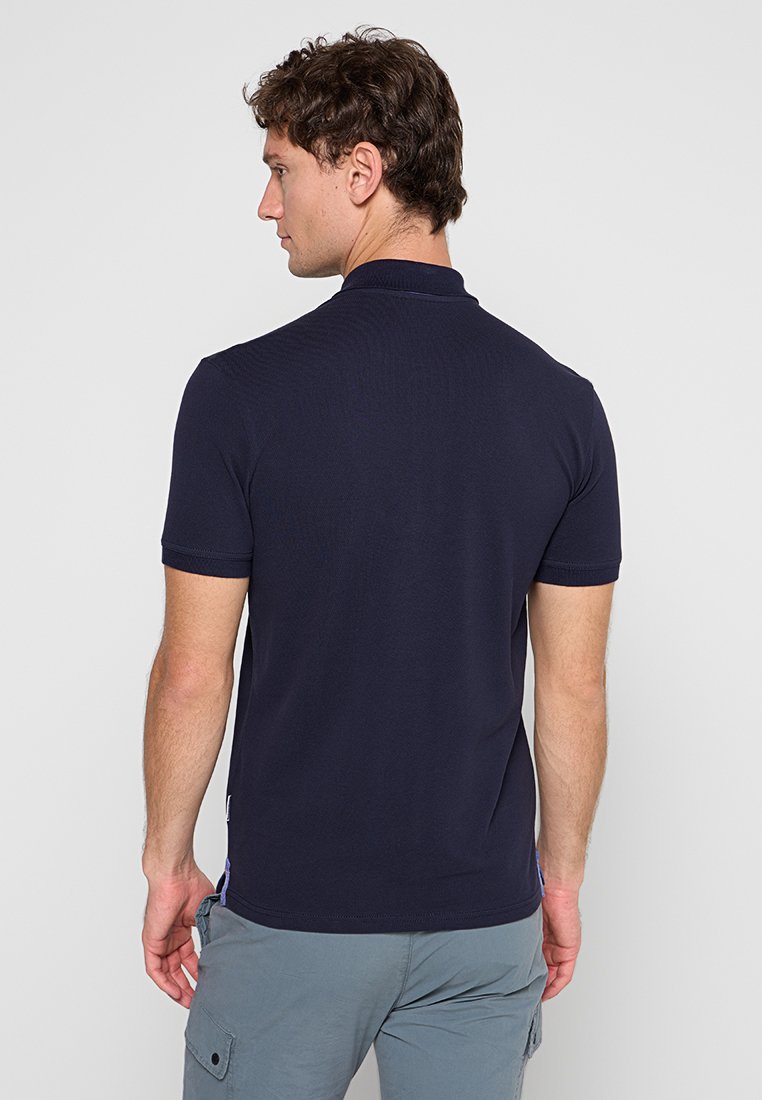 Marineblaues Poloshirt mit einem dezenten strukturierten Muster, kurzen Ärmeln und einem klassischen Kragen, von einem Modell von hinten präsentiert.
