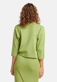 Lichtgroen gebreid sweater met driekwartmouwen. Geribbelde textuur met een cropped ontwerp, gecombineerd met een bijpassende geribbelde rok.