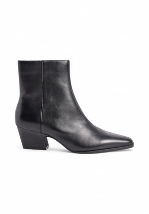 Stivale alla caviglia in pelle nera con punta affusolata e un tacco a blocco modesto. Texture liscia, design elegante, cuciture minime e senza hardware visibile.