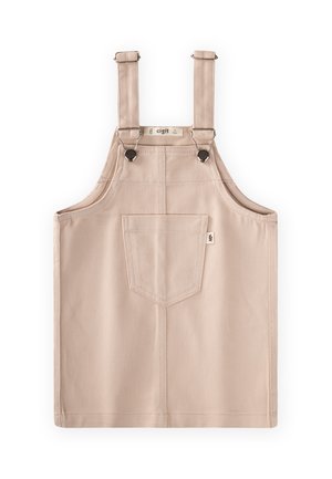 Mono vestido de algodón beige con bolsillo delantero, tirantes ajustables y cierres de botones metálicos, extendido sobre un fondo blanco.