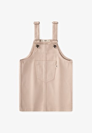 Beige katoenen overalljurk met voorkantzak, verstelbare bandjes en metalen knoopsluitingen, plat liggend op een witte achtergrond.