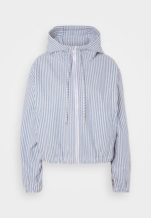Skrčena jakna v modro-beli črtasti tkanini, ki vključuje kapuco, sprednji zadrgo, elastične manšete in vrvico na robu.
