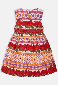 Robe florale avec un corsage smocké rouge, motifs roses et géométriques complexes en rouge, violet et jaune sur fond blanc.