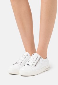 Vita lädersneakers med snörning, sidodragkedjedetalj, något förhöjd gummisula och en slät textur.