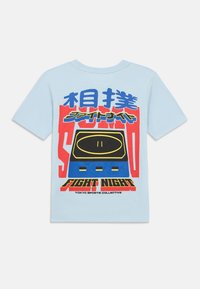 Svetlomodré bavlnené tričko s grafickým dizajnom v odvážnych červených, modrých a čiernych farbách, zobrazujúce text a vizuál ovládača.