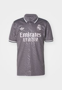 Ciemnoszara koszulka piłkarska Adidas Real Madryt z logo sponsora "Emirates Fly Better" oraz herbem drużyny na klatce piersiowej, z subtelnym wzorem i paskowanymi rękawami.