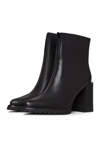 Bottines noires en cuir lisse. Bout carré, talon blocs haut et semelle en caoutchouc épais avec un motif de bande de roulement. Design sans couture sans fermetures.
