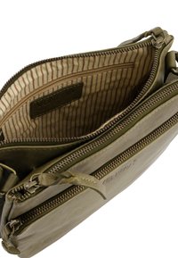Olivgrüne Leder-Umhängetasche mit zwei Reißverschlussfächern und beigem gestreiftem Innenfutter, das innen mit "Venezia" brandet.