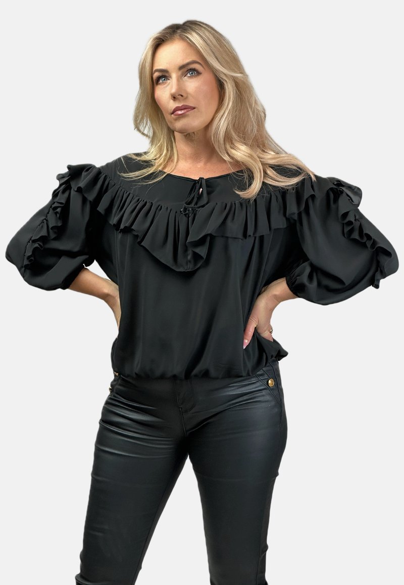Czarna bluzka z falbaniastym dekoltem i bufiastymi rękawami. Wykonana z gładkiego materiału, posiada wiązanie przy dekolcie oraz elastyczny dół.