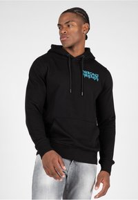 Sudadera negra con el texto "WRONG FRIENDS" en turquesa. Cuenta con un bolsillo tipo canguro, capucha ajustable con cordón, puños acanalados y dobladillo.