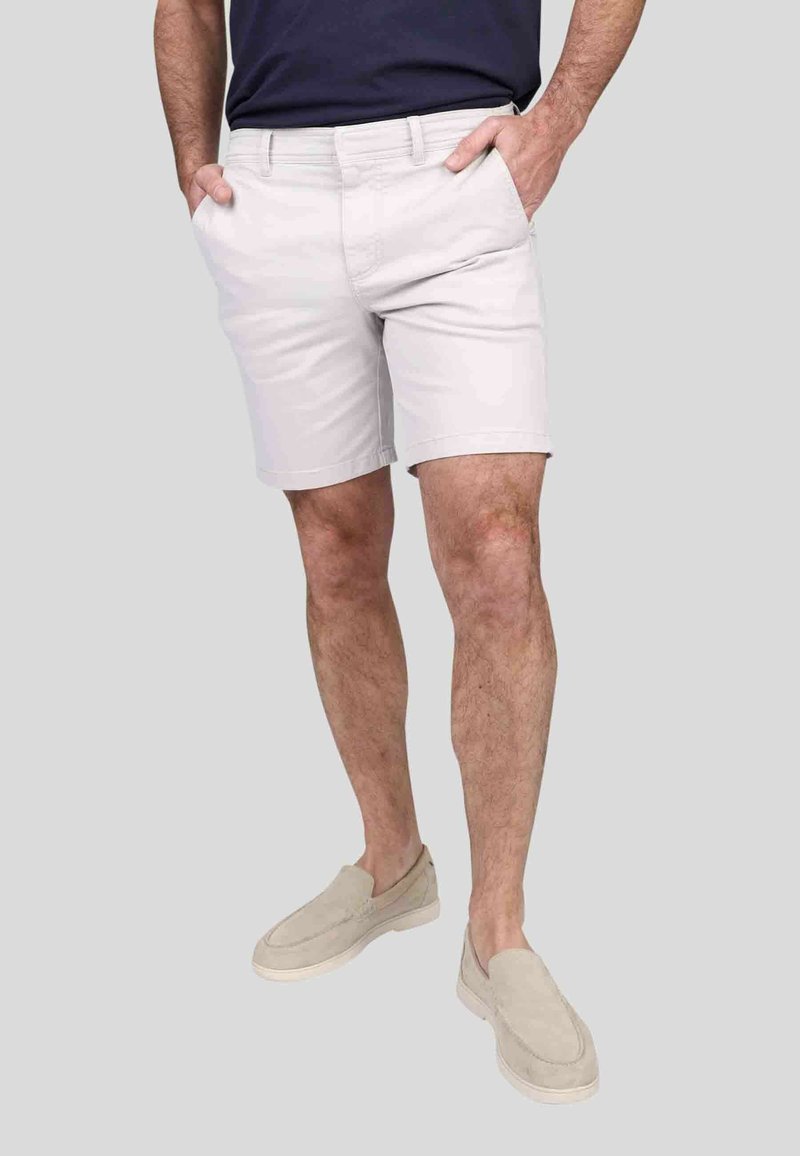 Shorts en coton gris clair avec une coupe décontractée, dotés de poches latérales et d'un devant plat. Accompagnés de chaussures à enfiler beiges.