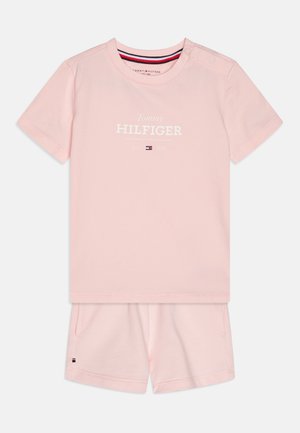 Világos rózsaszín pamut kétrészes szett, rövid ujjú T-pólóval, fehér logó felirattal és azonos színű, zsebes rövidnadrággal, márkás kiemeléssel.