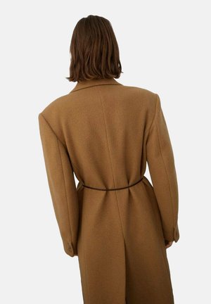 Manteau en laine marron avec un design structuré, grands revers et taille ceinturée. Il présente des manches longues et une finition douce et texturée.