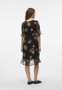 Zwart bloemenjurk met een doorschijnende overlay, voorzien van een ceintuurtje in de taille, fladdermouwen en een gerimpelde zoom, versierd met kleurrijke bloemetjespatronen.