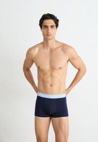 Marineblauwe boxershorts met een lichtblauwe elastische tailleband met daarop de merknaam "GANT." Gemaakt van zachte stof, ontworpen voor een snug fit.