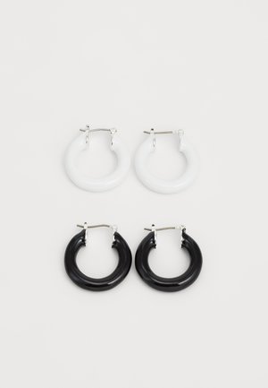 Obruče od sjajnog materijala: jedan par bijelih i jedan par crnih, svaki sa srebrnim hardverom i zaobljenim oblikom.