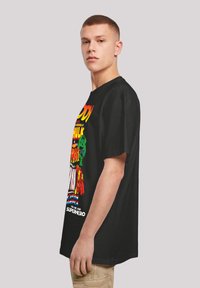 Black t-shirt featuring colorful graphic print with comic characters and text. Thick, relaxed fit; round collar; short sleeves; smooth texture.