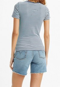 Randig t-shirt i nyanser av blått och vitt med rund halsringning, kombinerad med ljusblå denimshorts med fransade kanter och bakfickor.