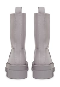 Botas altas grises hechas de cuero suave con una suela de goma texturizada, que cuentan con costuras visibles y pestañas en la parte superior para facilitar su uso.