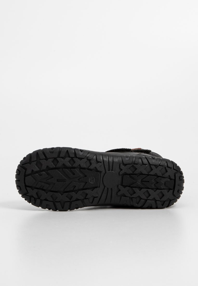 Schwarze Schuhsohle mit tiefen Rillen für besseren Halt, versehen mit einem zirkelförmigen Akzent in der Mitte und unterschiedlichen Profilmustern für Grip.