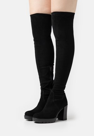 Bottes noires hautes en daim avec un talon épais, une fermeture éclair sur le côté et une texture lisse ; le design présente une silhouette ajustée.