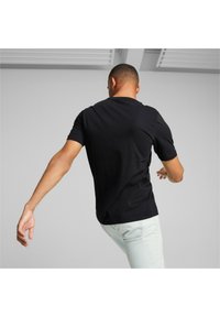 Camiseta negra de manga corta hecha de material suave, con cuello redondo y un corte relajado, combinada con jeans de color claro.