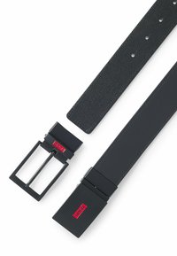Zwarte leren riem met een gestructureerd ontwerp, voorzien van een vierkante metalen gesp en een zwart-rood logo accent. Verstelbaar met meerdere gaten.