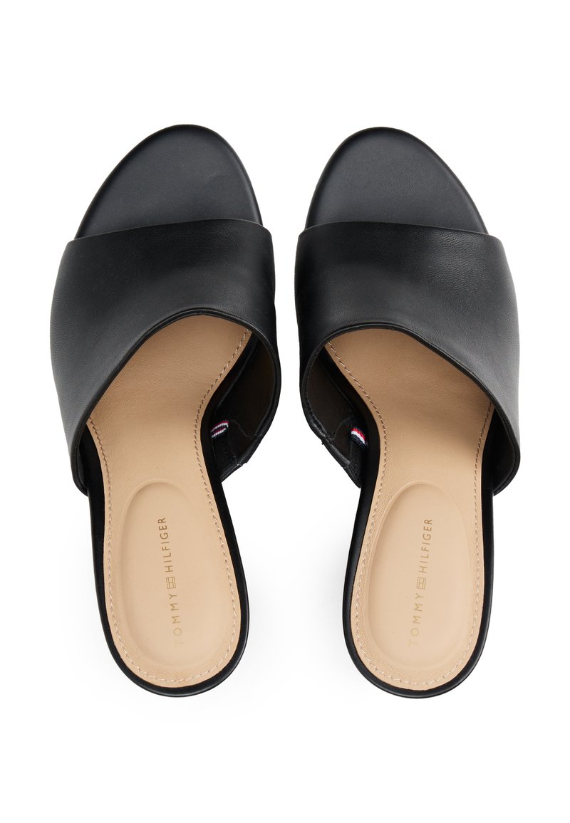 Schwarze Rutschen-Sandalen mit einem schlichten Kreuzbanddesign. Glattes Lederobermaterial, beiges Innenfutter und dezente Markenkennzeichnung auf der Fußsohle.