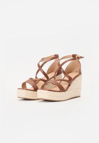 Sandales compensées en cuir marron avec des brides entrecroisées et une semelle en jute tressé, dotées d'une fermeture à boucle et d'une plateforme texturée.