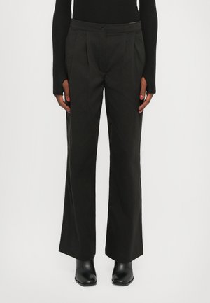 Wide-leg black trousers made of a smooth fabric, featuring front pleats and a button closure at the waist, styled with black ankle boots.