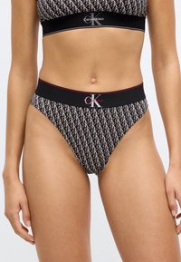 Μ πικίνι ασπρόμαυρο με μοτίβο λογότυπου 'CK'; ελαστικό ύφασμα; ελαστική ζώνη μέσης; ψηλό κόψιμο στα ανοίγματα για τα πόδια; κλασικός σχεδιασμός σλιπ τύπου thong.