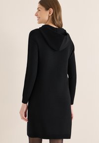 Abito maglione nero con maniche lunghe e cappuccio. Presenta una texture liscia e una silhouette aderente, con una lunghezza sopra il ginocchio.