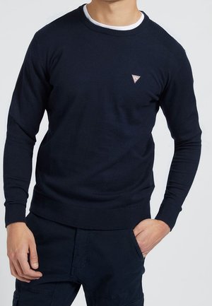 Marineblå strikket sweater med rund halsudskæring, ribbet manchetter og kant. Har en lille trekantet logo på brystet. Blød tekstur og tætsiddende design.