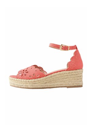 Korallrózsaszín ék talpú szandál bokapánttal, hullámos szélű, kivágott virágmintás szövet felsőrésszel és fonott juta talppal.