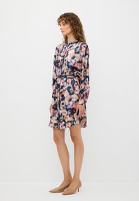 Blommönstrad klänning med långa ärmar, lättviktig tyg, insydd midja och längd ovanför knäet. Har olika nyanser av rosa och blått.