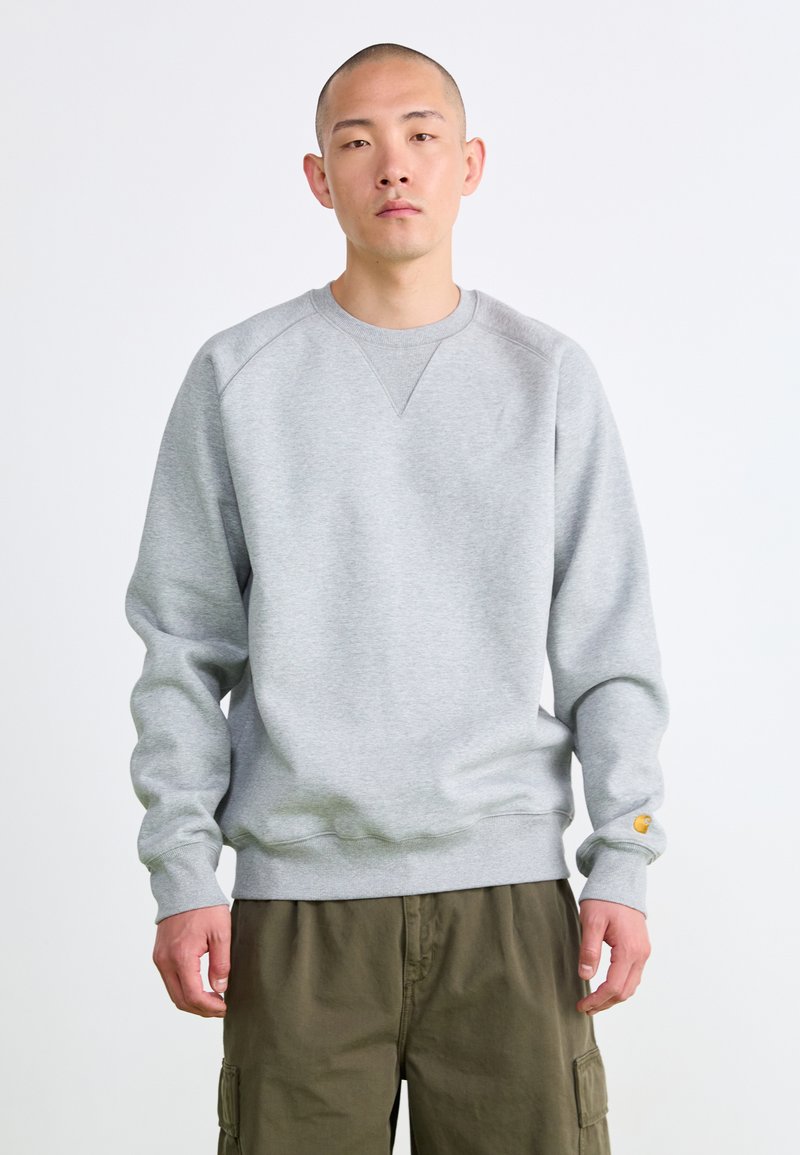 Sweatshirt en coton gris avec un col rond, des poignets et un ourlet côtelés. Présente un petit patch logo sur la manche gauche.