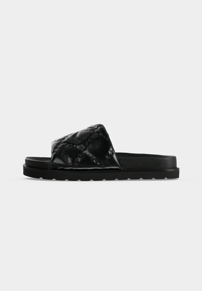 Μαύρο σανδάλι slip-on με χοντρή σόλα και φαρδιά, καπιτονέ λουράκι με διακριτικό ανάγλυφο μοτίβο, εμφανίζεται από το πλάι σε λευκό φόντο.