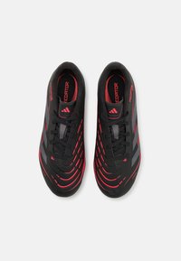 Zapatillas deportivas negras con acentos rojos, que cuentan con superposiciones texturizadas, un diseño aerodinámico y rayas en contraste. Cierre con cordones.