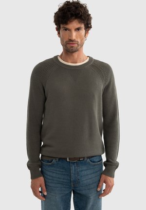 Olivroheline kudum, ribakonstruktsiooniga, ümmarguse kaelusega ja ragslansleeved, kaasas siniste denimsteemadega. Lihtne disain, ilma mustriteta.