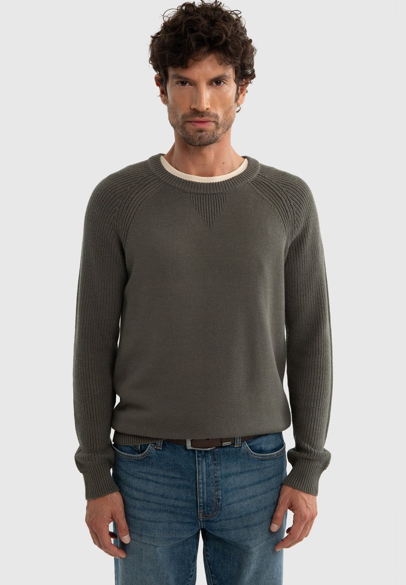 Olivroheline kudum, ribakonstruktsiooniga, ümmarguse kaelusega ja ragslansleeved, kaasas siniste denimsteemadega. Lihtne disain, ilma mustriteta.