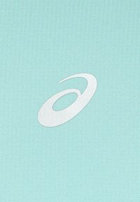 Un tessuto blu acqua chiaro presenta una texture liscia con un prominente logo circolare bianco al centro, che mette in mostra un design minimalista.