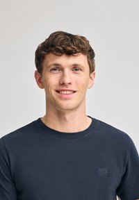 Ciemnoniebieski sweter z okrągłym dekoltem wykonany z bawełny. Posiada małe haftowane logo na piersi. Gładka tekstura, dopasowany krój.